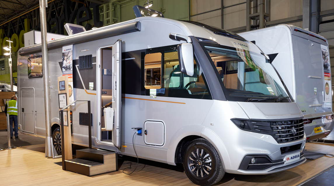 Adria Supersonic 780 SL exterior, the A class is silver, the habitation door is open showing into the interior, with a double step to gain easy access.  The two roof lights are fully open.