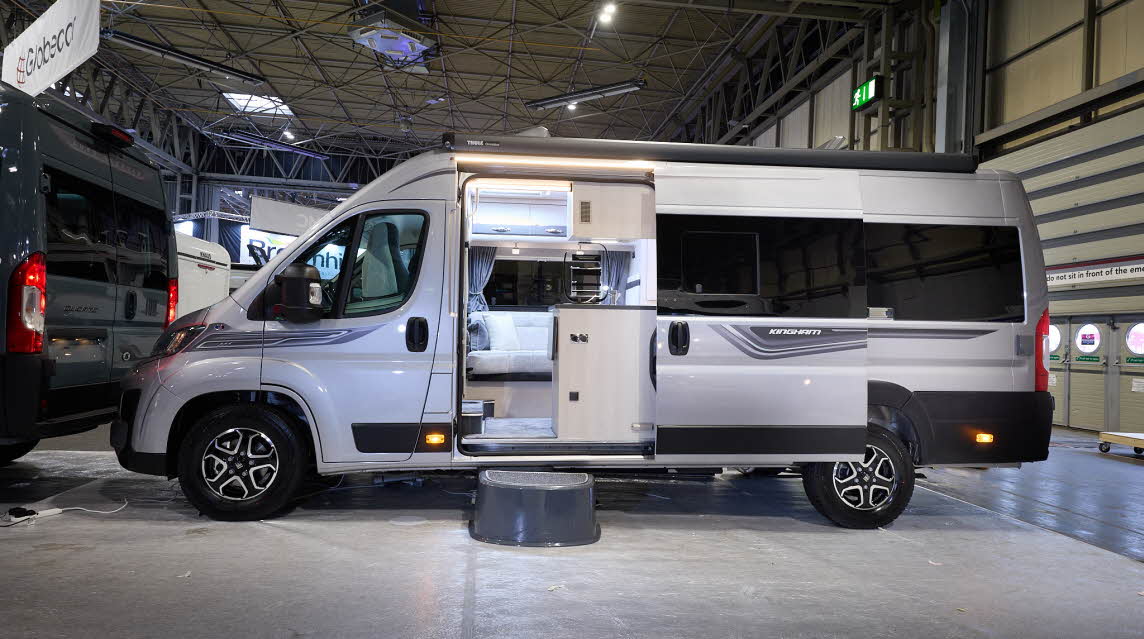 The Auto-Sleeper Kingham has a silver exterior with black/grey decals.  There is a black step by the open sliding door.