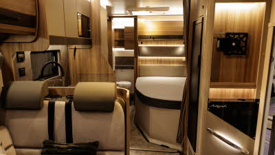 The Bailey Autograph 79-4F has beige and brown upholstery.  The rest of the interior matches these shades.  There is a fixed bed and there is a brown privacy curtain to separate the bedroom.  The washroom is at the rear.