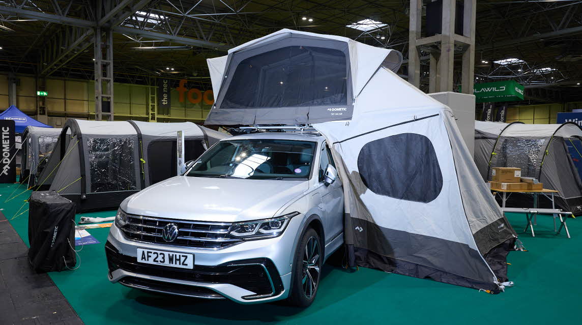 The Dometic TRT 140 AIR is displayed on a silver Volkswagen.  It has grey and white canvas and has an annex to the side of the vehicle.