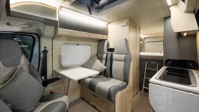 Auto-Trail Expedition 68's interior has two tone grey leather and fabric.  The furniture is wooden and the rear seats have fitted seatbelts.  There is a fixed bed to the rear with a ladder to gain easy access. The kitchen sink and hob is to the right