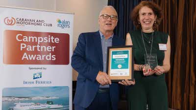 A Caravan and Motorhome Overseas Campsites Award Winner with the Chairman next to a sign showing Campsite Partner Awards, with Irish Ferries below it