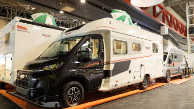 The Pilote P740FC Evidence has a black cab and a white coachbuilt body with black/red decals.  There are two green and white striped umbrellas on its roof.