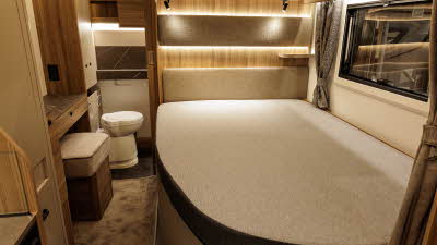 The Bailey Autograph 79-4F's bedroom has a French transverse bed with a dressing table opposite.  The washroom is at the rear, its sliding door is open revealing the toilet.