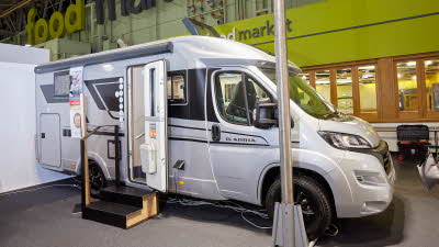 Adria Compact Supreme DL exterior, the motorhome is white with grey decals, the habitation door is open showing into the interior, with a double step to gain easy access. The roof lights are fully open.