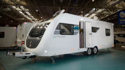 Swift Sprite Grande Quattro FB has a white exterior with grey and turquoise graphics, it has a black panel under the front window and its skylight is open.  It has a twin axle.