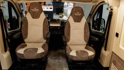 The WildAx Motorhomes Solaris XL has brown and cream upholstery.  The two front seats are swivelled and face into the van.