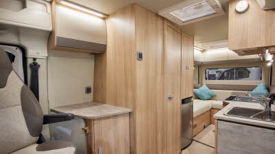 Auto-Trail V-Line 635 Sport has cream upholstery, with wooden furniture.  The floor has beige carpet.  The overhead lockers are cream.  The kitchen has a square sink and a flap to extend kitchen work surface.  The vehicle has a rear lounge.