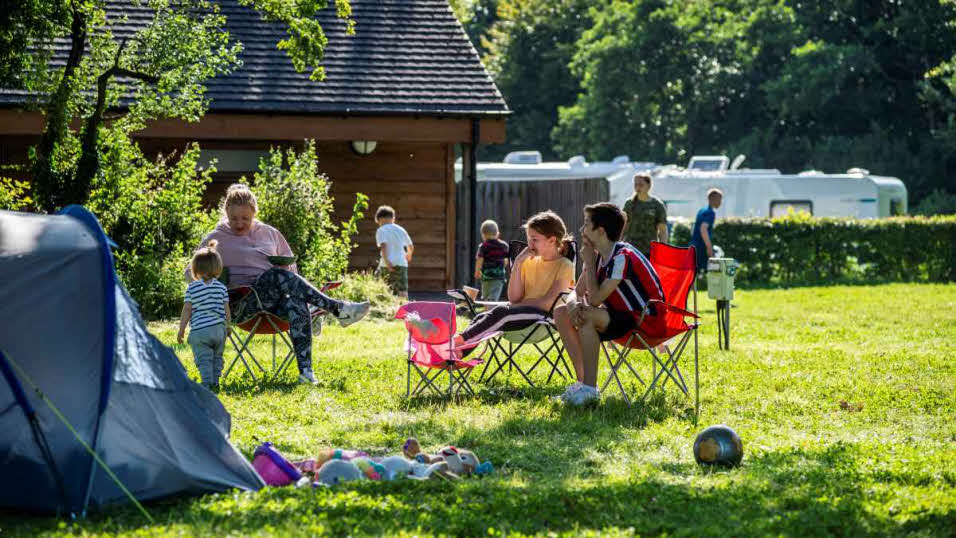 Young family sitting outside a tent