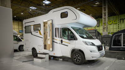 Eura Mobil Activa One’s exterior is white with grey and gold decals.  The habitation door is open and there is a step to gain easy access. 
