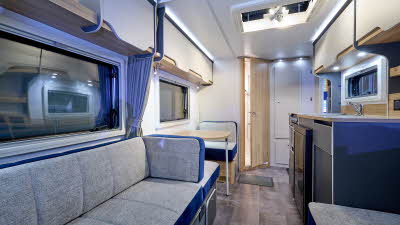 Bailey Discovery D4-4L interior, grey and blue upholstery, pale wood cabinets, open skylight, wooden door which is slightly open