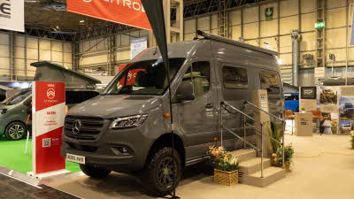 The RP Motorhomes Rebel U is dark grey and has three steps with metal hand rails to gain easy access.  There are flowers either side of the steps.