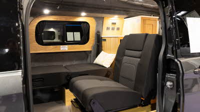The Rolling Homes Camper Ltd Livingstone has black upholstery and one of the passenger's chairs has been folded flat as a bed. 