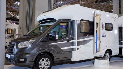 Auto-Trail F-Line F62 exterior, the motorhome has a black cab with white body, the habitation door is open showing into the interior, with a step to gain easy access.  There is a blue Auto-Trail umbrella in the door.