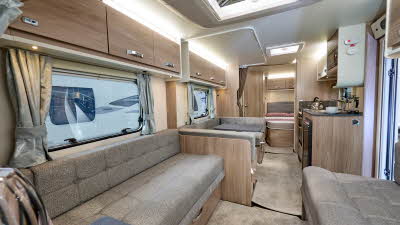 Swift Sprite Grande Quattro FB's interior has wooden furniture with beige upholstery and carpet.  The bedroom is to the rear.  The skylight is open.