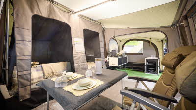 In the Camp-Let Earth’s main tent there is a dining table and chairs.  Both bedroom doors are open. The kitchen area is at the rear.