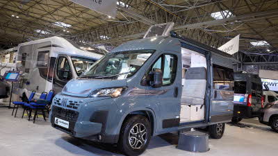 The Auto-Sleeper Symbol has a grey exterior.  There is a black step by the opening sliding door which reveals the rear passenger seats.