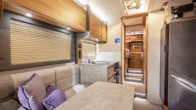 Bailey Adamo 75-4T has beige upholstery, with wooden overhead lockers.   The kitchen has a round sink and a flap to extend kitchen work surface.  The vehicle has a rear bedroom with two fixed single beds.