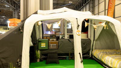 The OPUS Full Monty has brown and white canvas.  It has a bed to the left of the photo with bunting hanging from the roof.