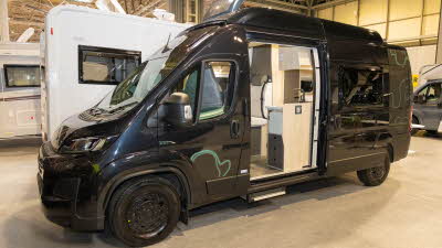 The Xplore CV X9 is black with turquoise decals.  Its sliding and rear doors are open.  