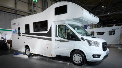Rimor Kilig 9’s exterior has white body with grey decals.  There is a window in the overcab section.  There are three steps to gain easy access however its rear habitation door is closed.