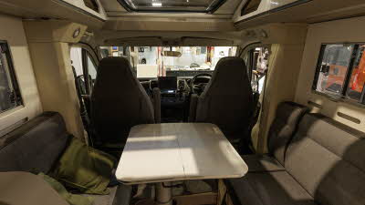 The Adria Compact Supreme DL has grey upholstery with leather trim.  It has a white extendable table.  There is a large sunroof.