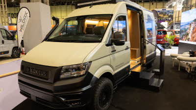 The Kaktus Adventure Vans Oasis is cream.  Its sliding door is open and there are three black steps to gain easy access.  