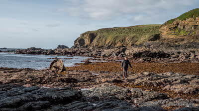 Man walking on a pebbled beach at the coast