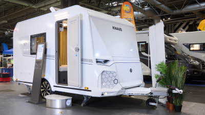 Knaus Yaseo 340PX’s exterior is white with a hexagon pattern beside the front locker.  It has no front window.  The entrance door is open with a step to gain easy access.  There is an information board to the left of the door.  