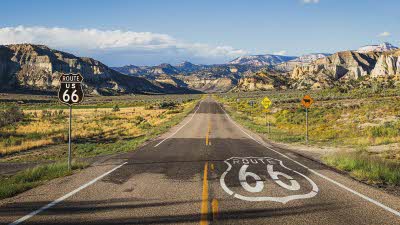 Scenic road with route 66 sign on the tarmac on the road heading towards the mountains in the distance