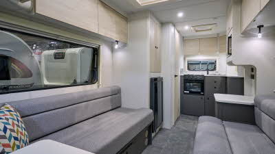 Xplore XC DUO's interior has grey upholstery with pale wooden furniture.  Its kitchen is at the rear with dark grey units.