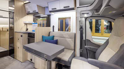 The Sun Living S Series 75SL has grey carpet and its upholstery is grey with cream inserts.  The cabinets are white and dark wood.  Towards the rear there is a fixed bed.