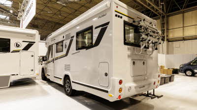 The Benimar Primero 282 has a white exterior and is decorated with black and yellow decals.  There is a bicycle rack fitted to the rear.