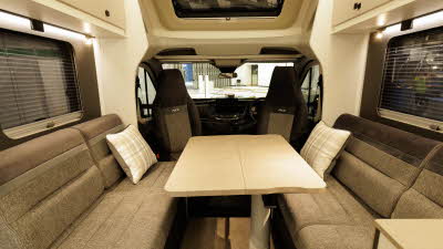 The Ace Motorhomes 1500 SL has two tone brown upholstery.  The front seats are swivelled to face the cab and are positioned around the extended table.  There are two cushions on the front bench seats.