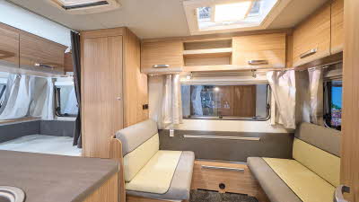 Weinsberg CaraOne 390 QD's interior is primarily wooden with two tone cream and grey seating.  The fixed bed is to the rear.  There are two skylights/