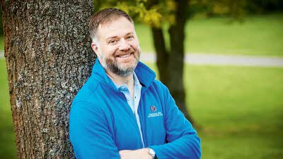 Director General, Nick Lomas, leaning against a tree