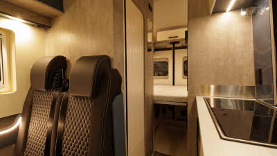 WildAx Motorhomes Equinox 2WD has brown upholstery with wooden panelling, the hob is to the right.  At the rear there is the fixed rear bed.