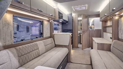 Swift Challenger Exclusive 480’s interior has wooden units with beige upholstery which has embossed patterns.  The rear door is open revealing the washroom