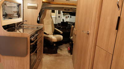 The Auto-Sleeper Broadway EL has wooden furniture, the kitchen is towards the front.  The passenger's front seat is swivelled to face the motorhome.  There is a large skylight above the cab.