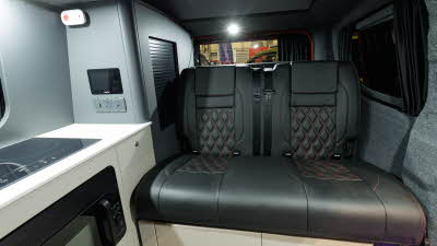 The Bespoke Leisure Bespoke Explore PHEV has black upholstery, its cabinets are white.  There is an induction hob on the left.