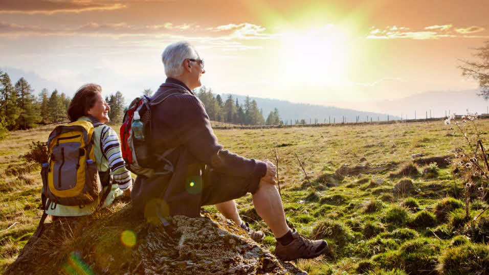 Elderly couple sitting on a rock in a wide open field