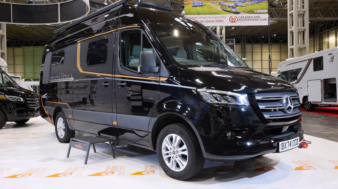 The Malibu Genius 641 LE is black with gold decals.  There is a black step by the slding habitation door.  The front sunroof is open, as are the rear doors.