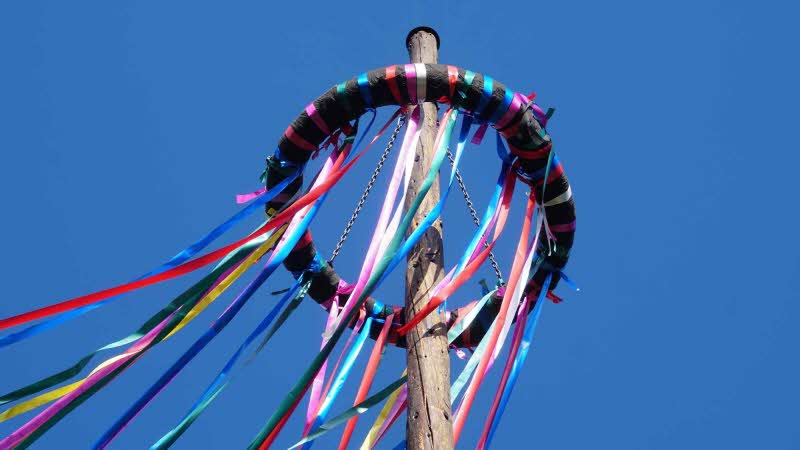 Colorful Festive Ribbons And Beautiful Blue Sky Background. Maypole Set-Up, Customs With A Long Tradition, Germany. 