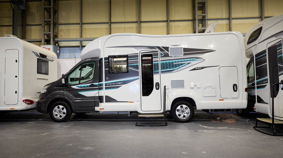 The Swift Voyager 540 has a black cab with a white body and grey, black and turquoise decals.  There are two steps outside the closed habitation door.