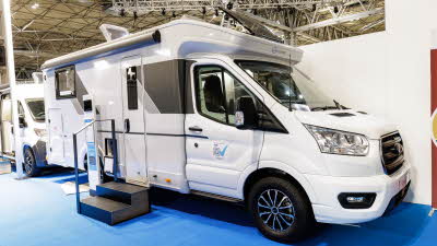 The Sun Living C Series 70 DL's exterior is white with black and grey decals.  There are two steps outside the habitation door to enable easy access.  Its sunroof and skylights are open.