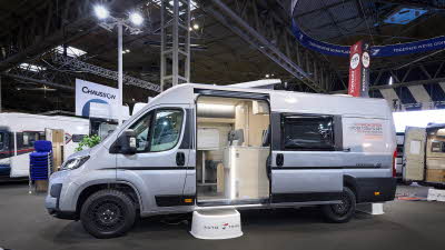 The Auto-Trail Expedition 68 is silver with black decals. There is a white step by the open sliding door which reveals the interior.
