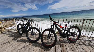 Two mountain bikes leaning against railings with the ocean and blue sky behind