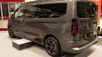 The Hillside Leisure Cromford is dark grey, its rising roof and sliding door are closed.  There is a step in front of the sliding door.