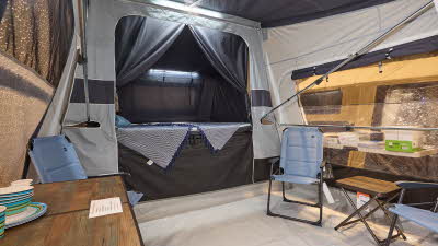 In the Jamet Compact Eco there are three blue chairs, a table and a coffee table. The bedroom door is open. There is lighting on the ceiling.