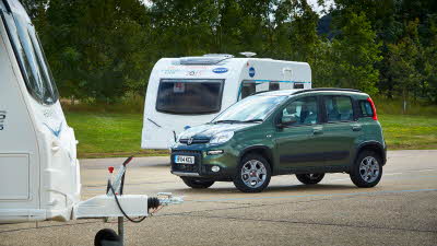 Green Fiat Panda parked next to two small caravans